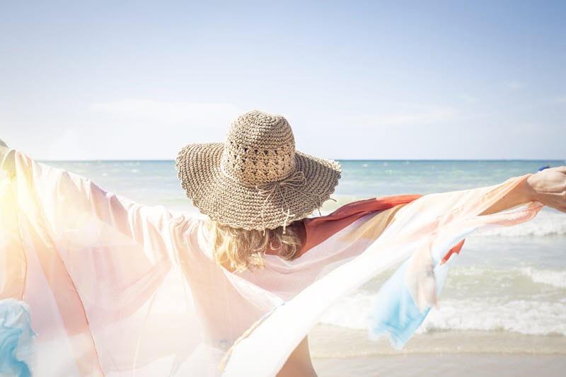 woman looking at water with arms outstretched