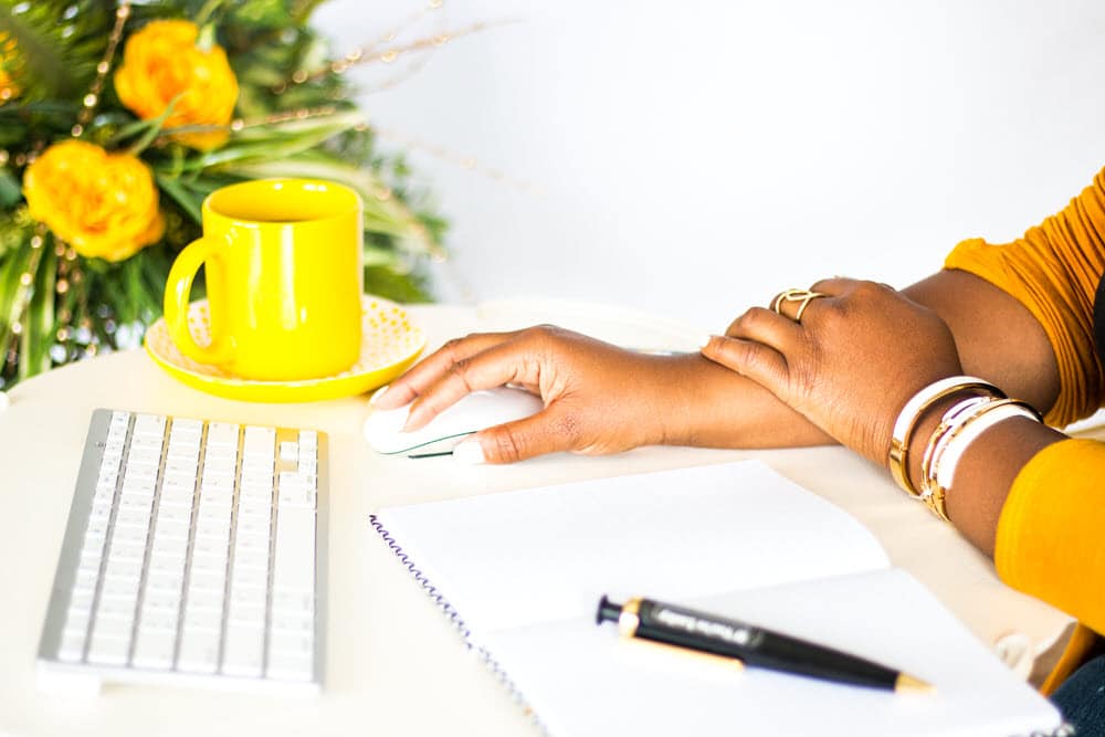 woman working on computer yellow shirt